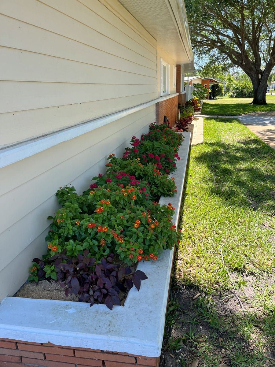 A planter filled with flowers is on the side of a house.