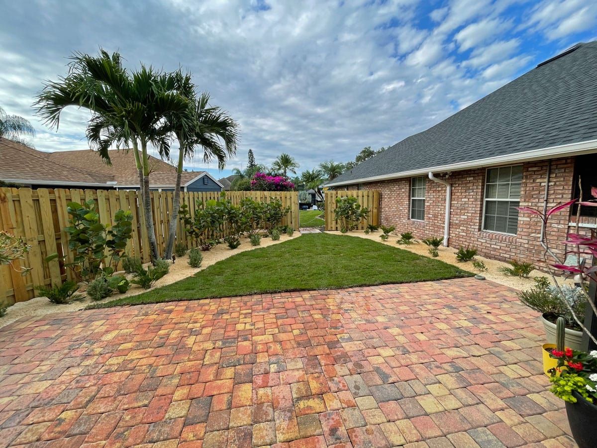 A brick driveway leading to a house with a lush green lawn.