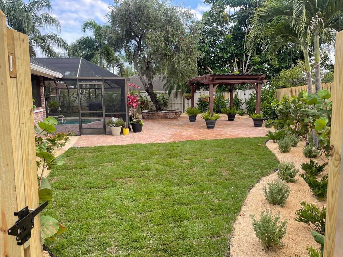 A backyard with a wooden fence and a lush green lawn.
