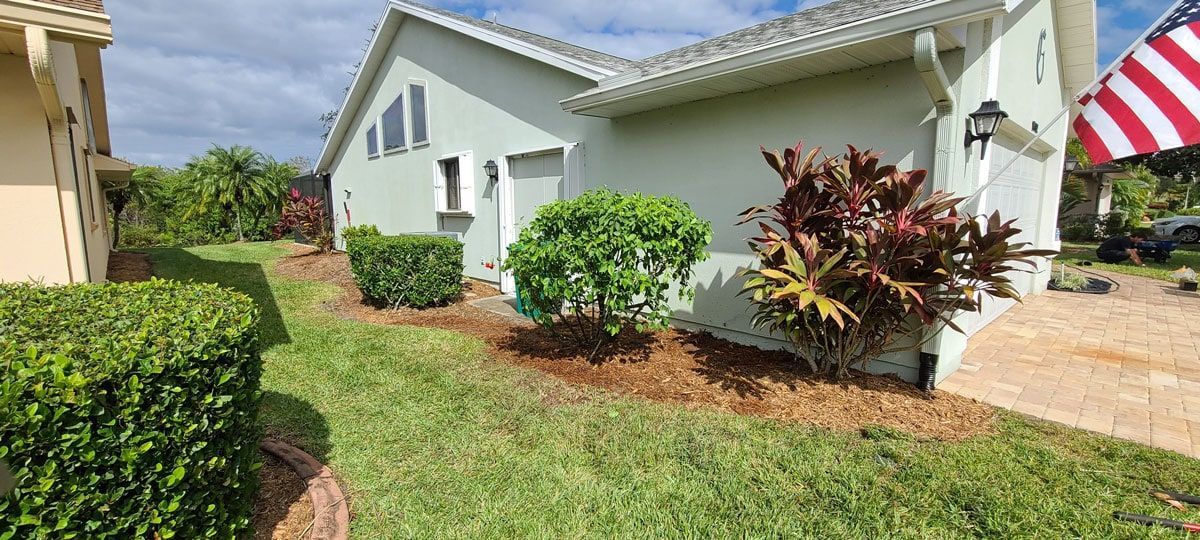 A house with a flag in front of it and a lush green lawn.