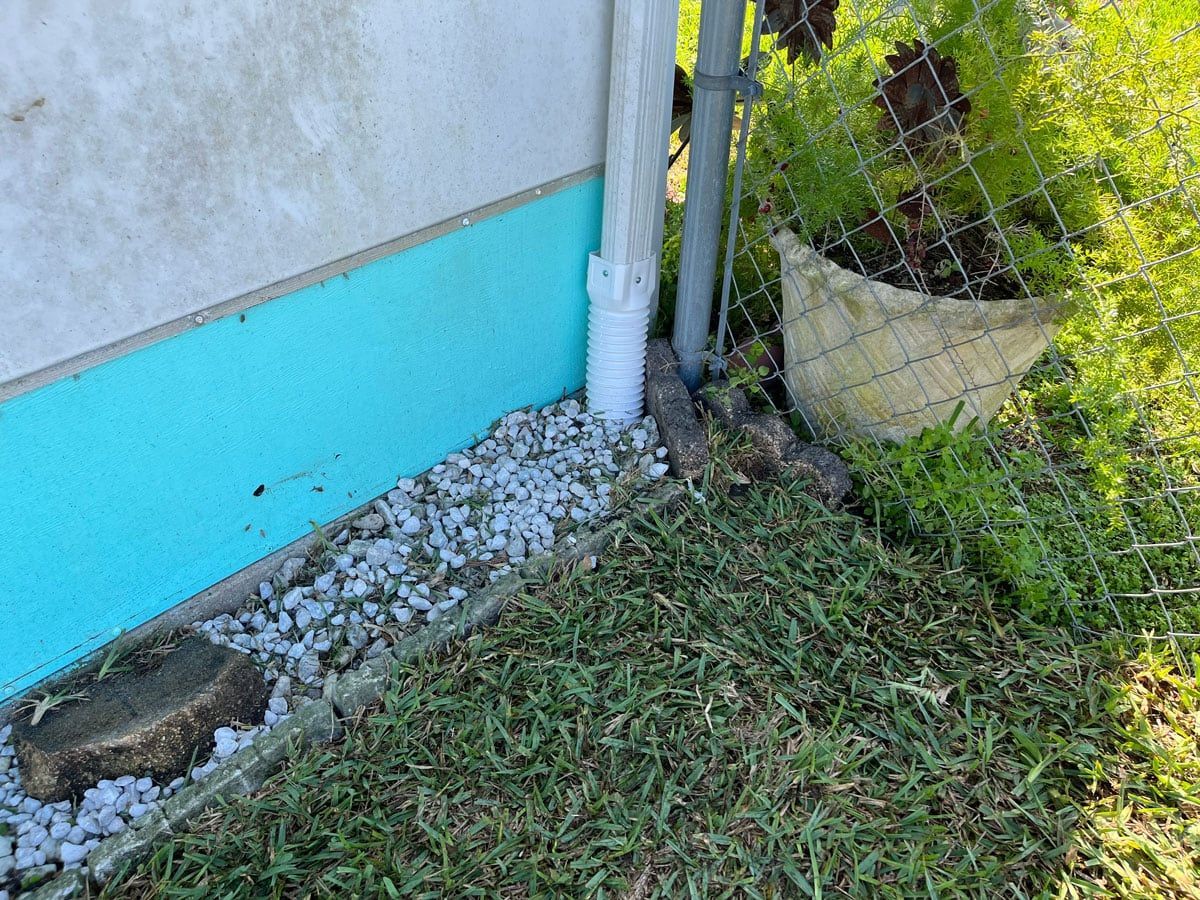 A drain pipe is sitting in the grass next to a fence.