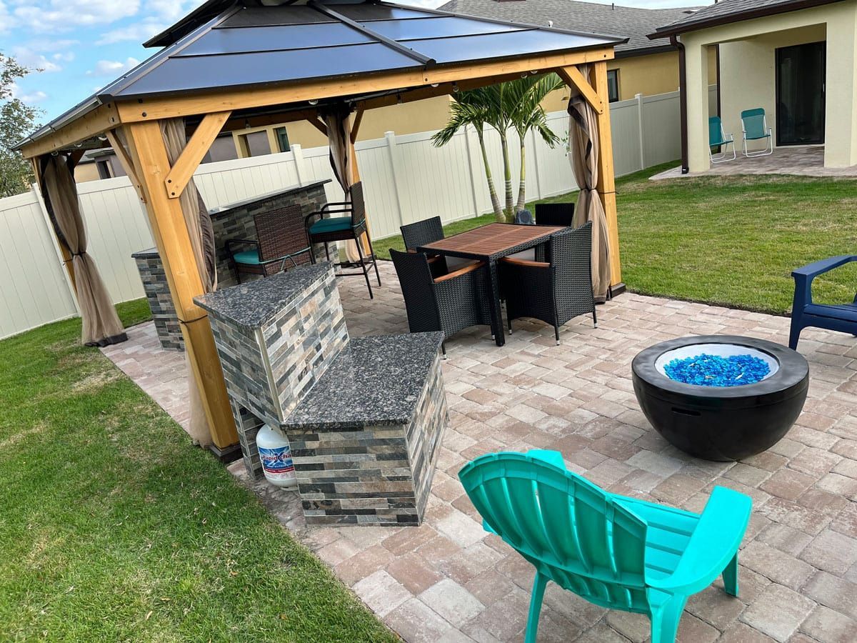 There is a gazebo in the backyard with a fire pit and chairs.