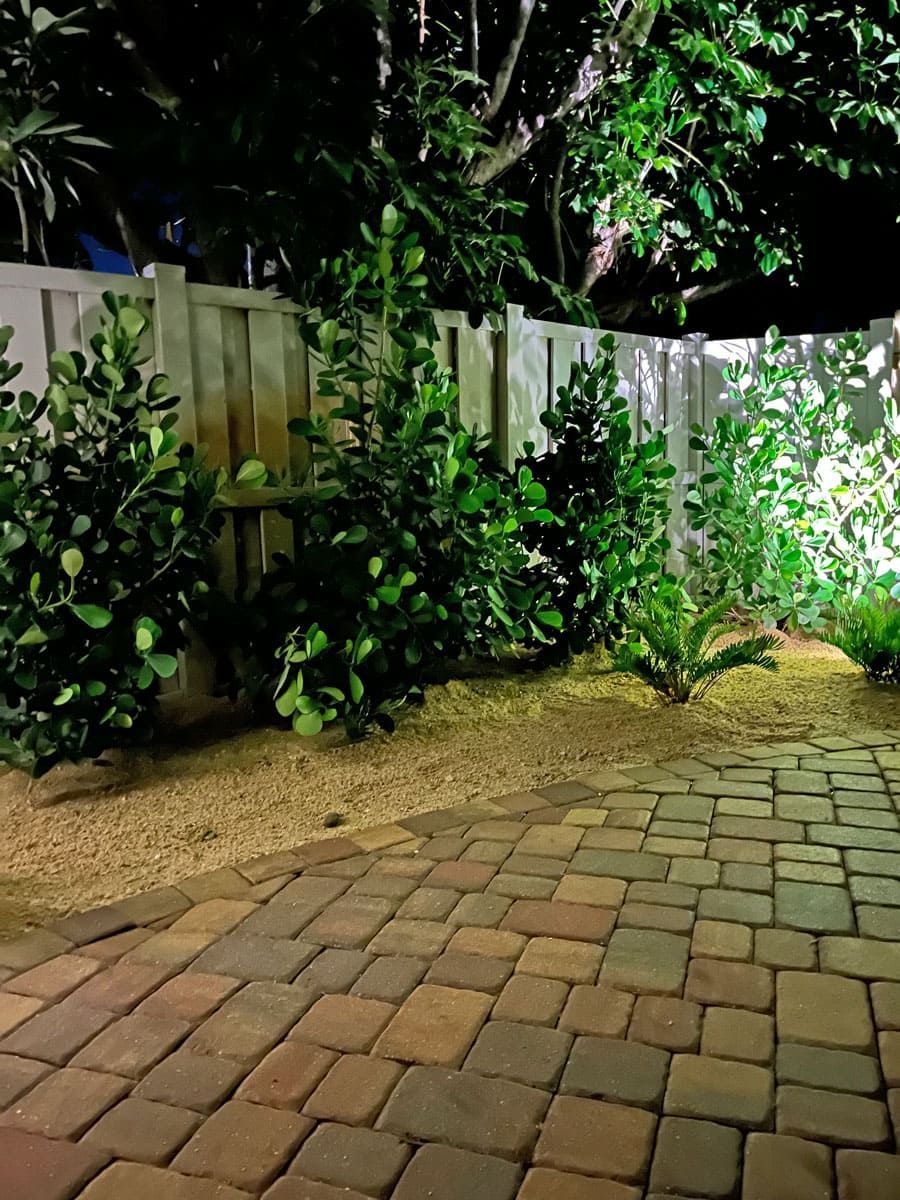 A brick walkway with a wooden fence in the background