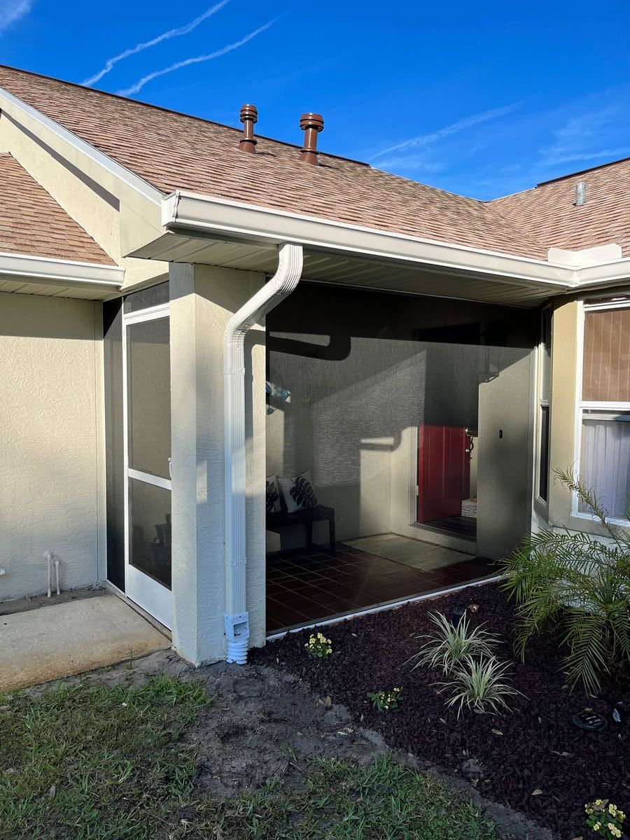 A house with a screened in porch and a gutter on the side of it.