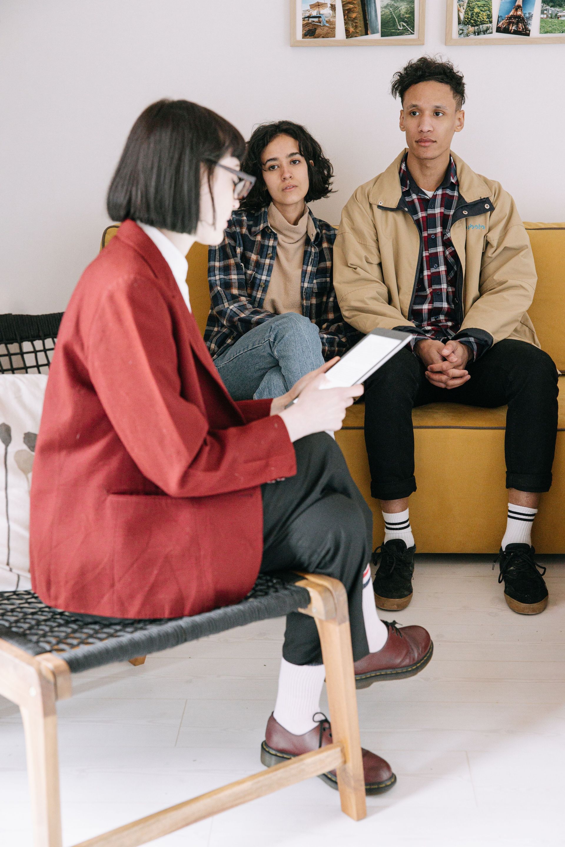 Un consejero conversa con dos clientes sentados en una sala de estar luminosa durante una consulta