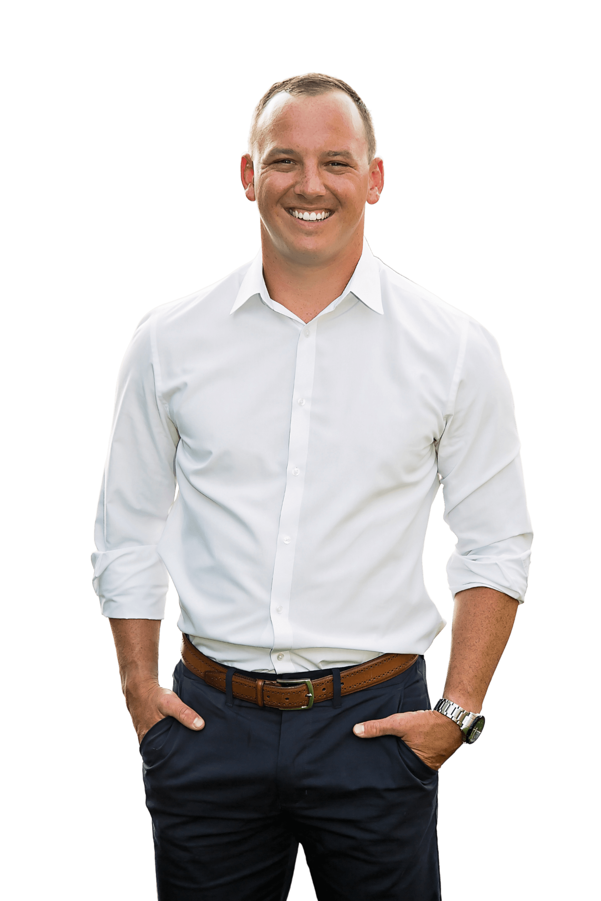 Smiling man in a white dress shirt and dark pants, standing with hands in pockets on a white background