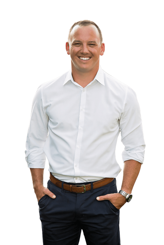 Smiling man in a white dress shirt and dark pants, standing with hands in pockets on a white background