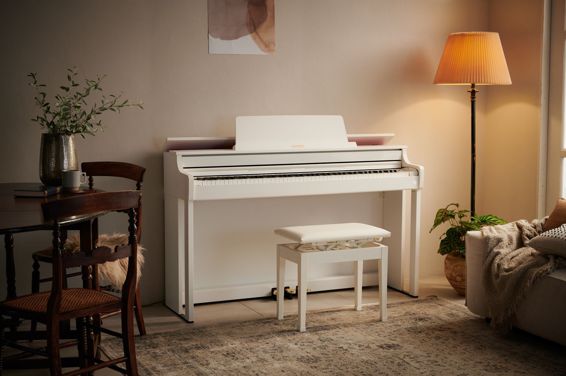 Ein weißes Klavier steht in einem Wohnzimmer neben einem Tisch und Stühlen.