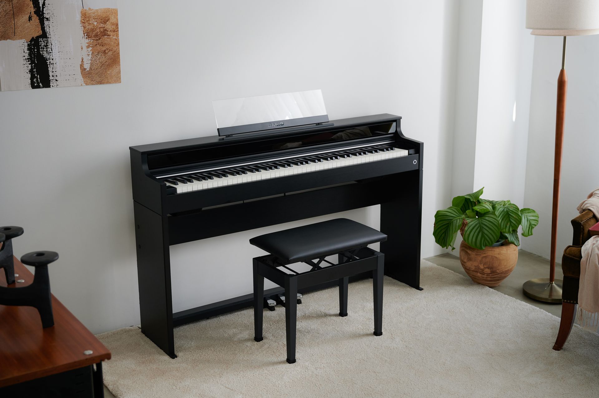 Ein schwarzes Klavier steht in einem Wohnzimmer neben einer Bank.