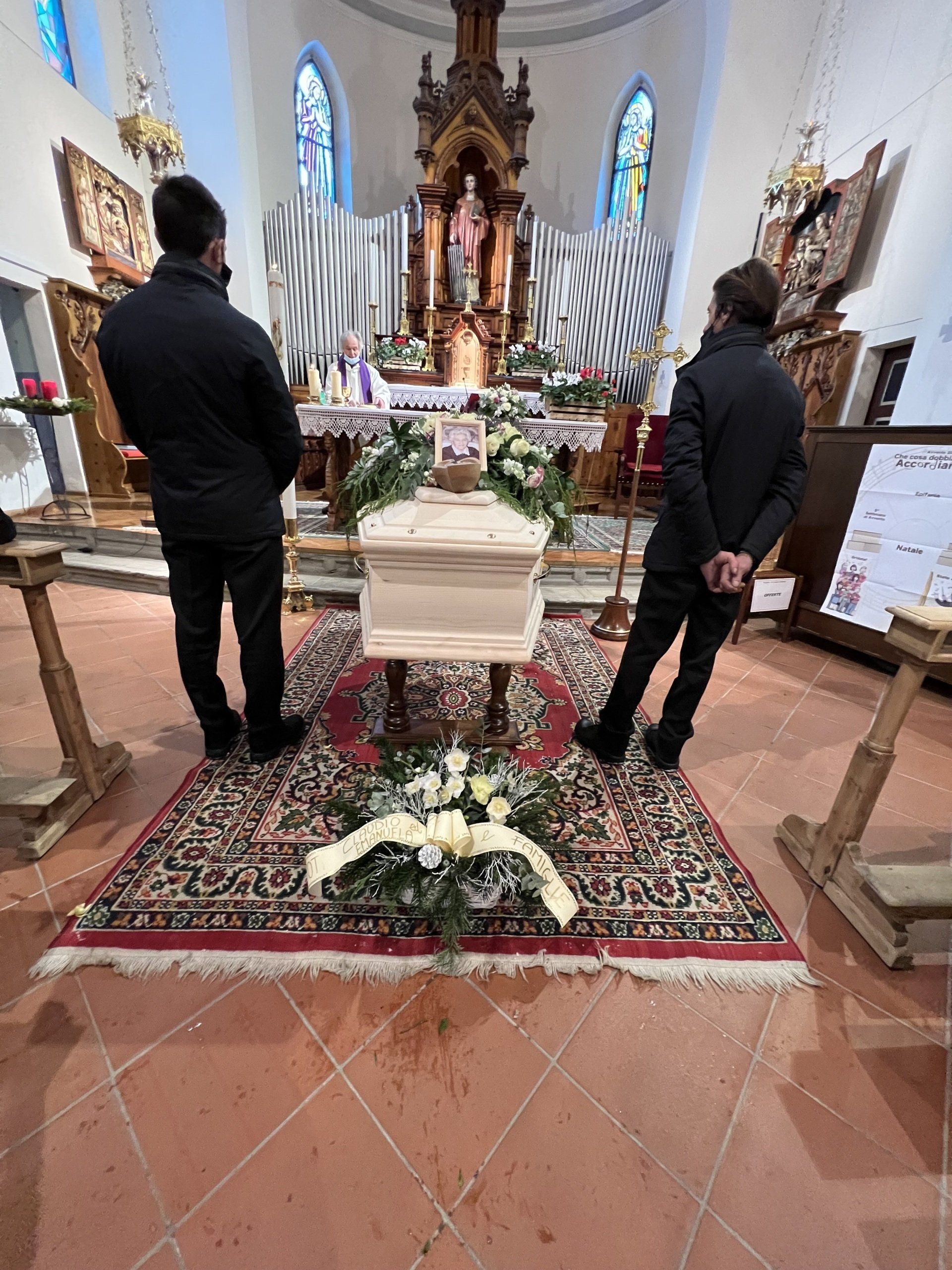 Due uomini sono in piedi davanti a una bara in una chiesa.