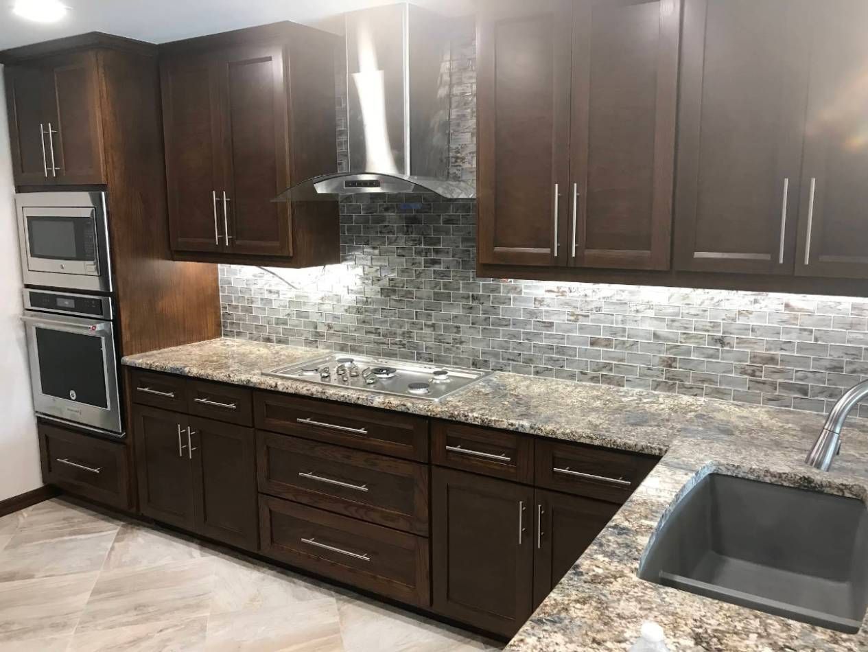 Modern kitchen with dark wood cabinets, mosaic tile backsplash, granite countertops, and stainless appliances