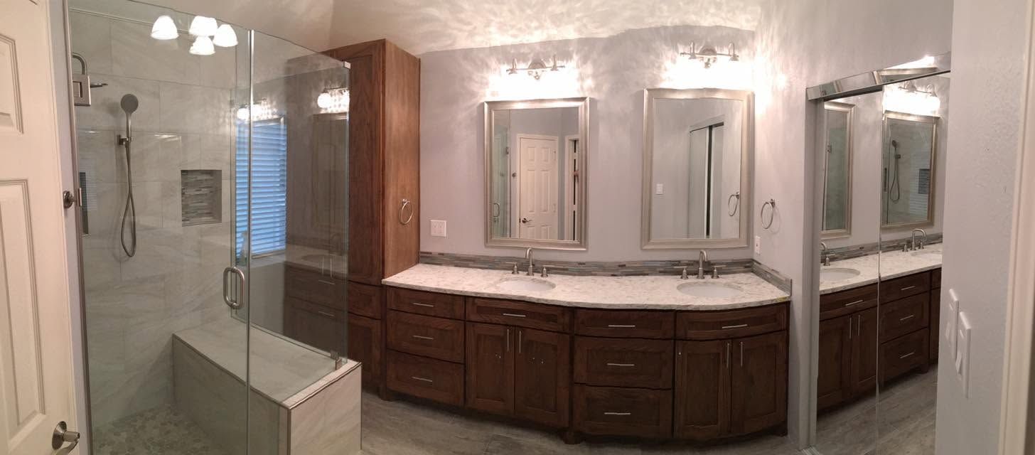 Spacious bathroom vanity with double sinks, large mirrors, dark wood cabinets, and a glass shower on the left
