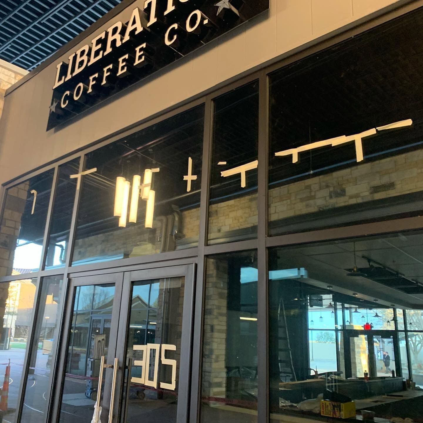 Storefront of Liberation Coffee Co. with glass doors and windows, seen in a bright urban setting