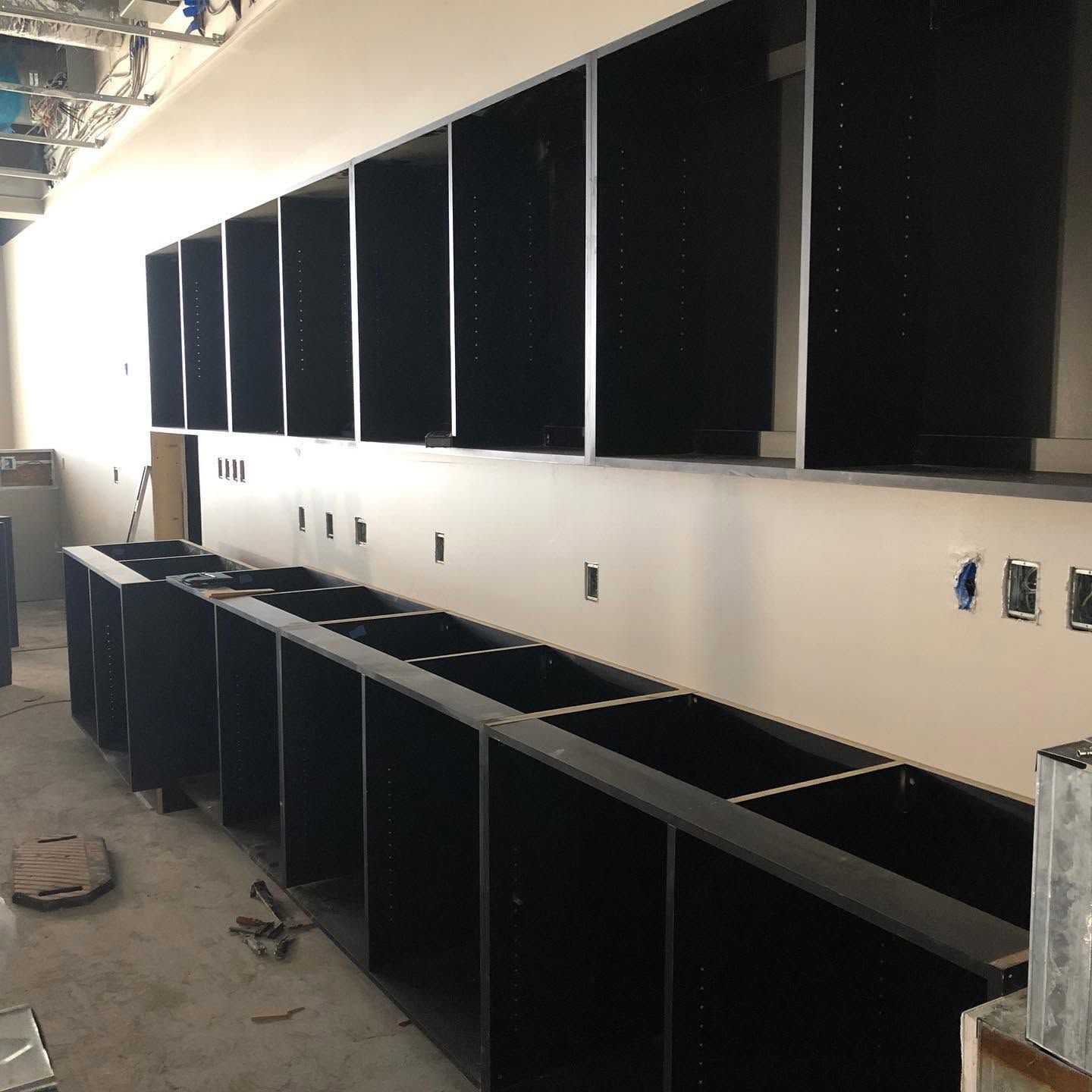 Unfinished kitchen with black cabinets and counters along a wall, seen during renovation.
