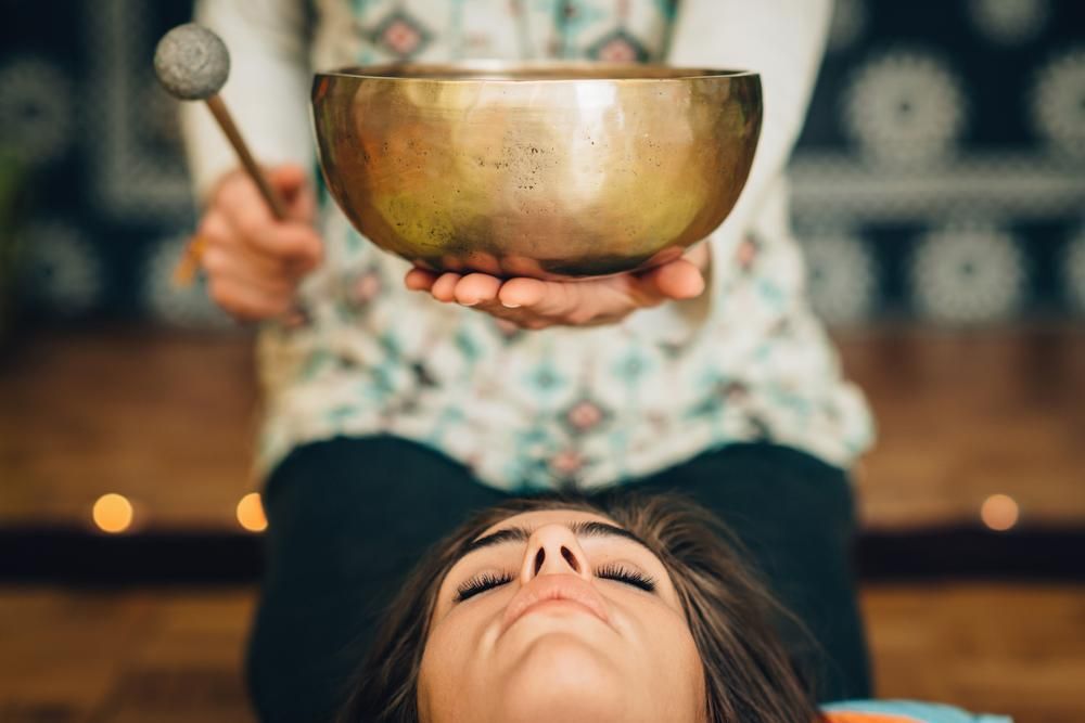 A Woman Is Holding a Singing Bowl Over a Woman's Head — Beauty In Profile In Salamander Bay, NSW