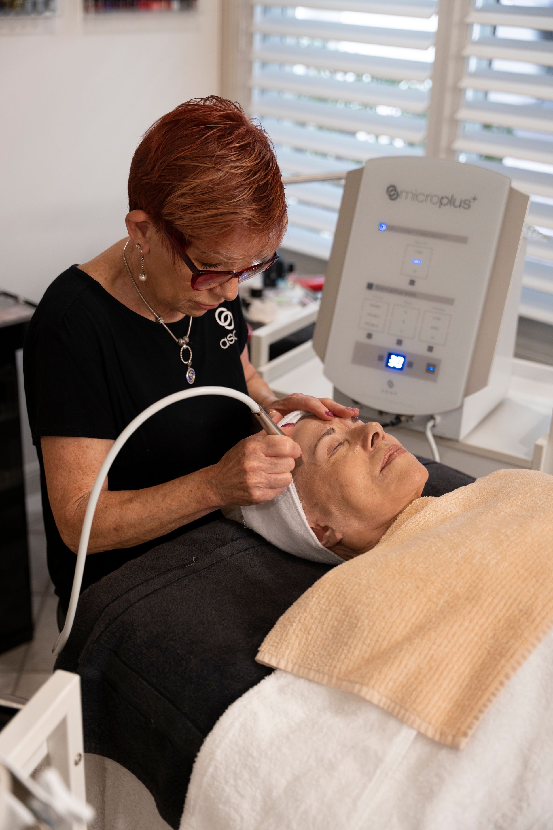 Woman Performing a Facial Treatment on A Client with A Device in A Salon Setting — Beauty In Profile In Salamander Bay, NSW