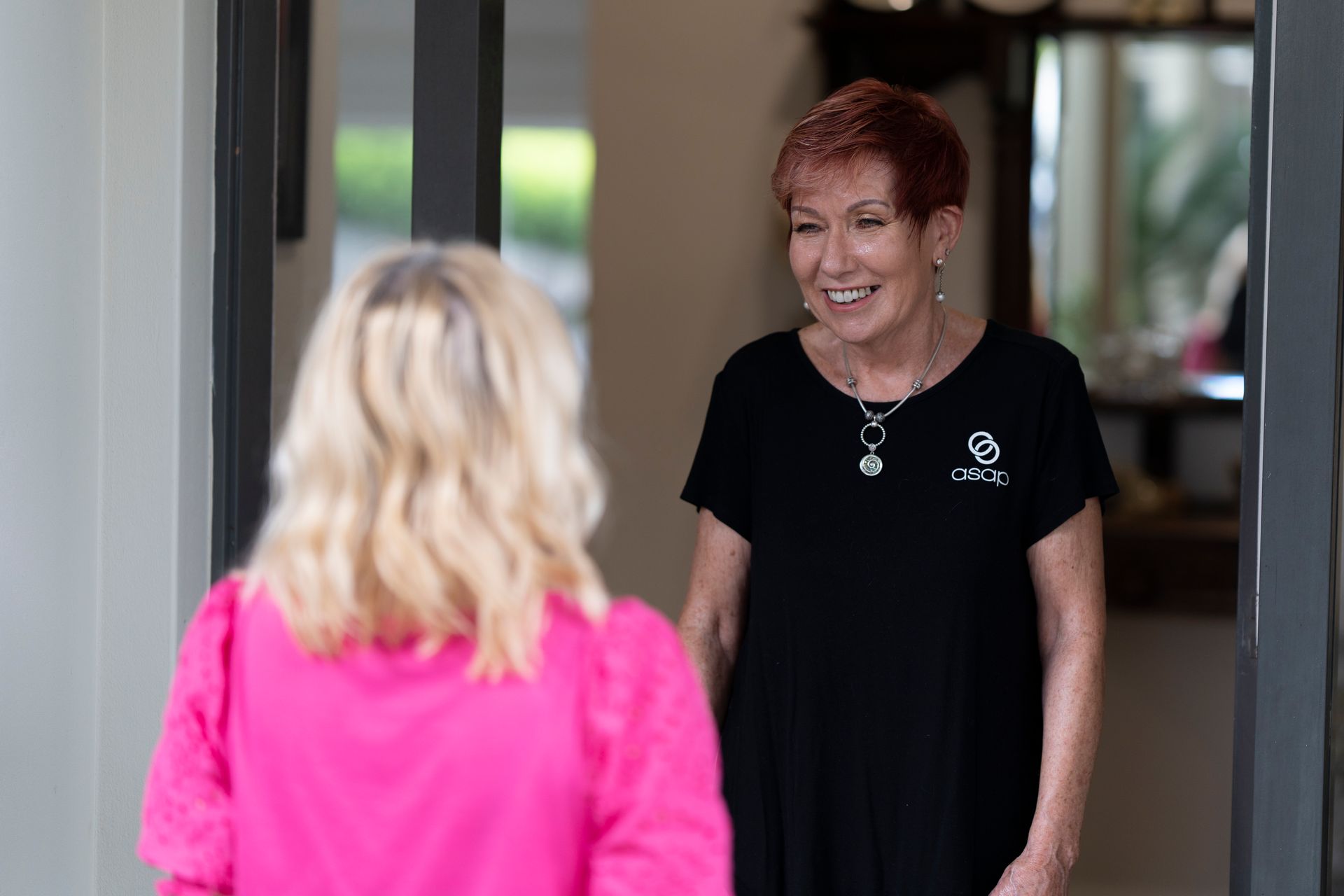 Woman with Red Hair Smiling at A Person in Pink, Inside a Doorway — Beauty In Profile In Salamander Bay, NSW