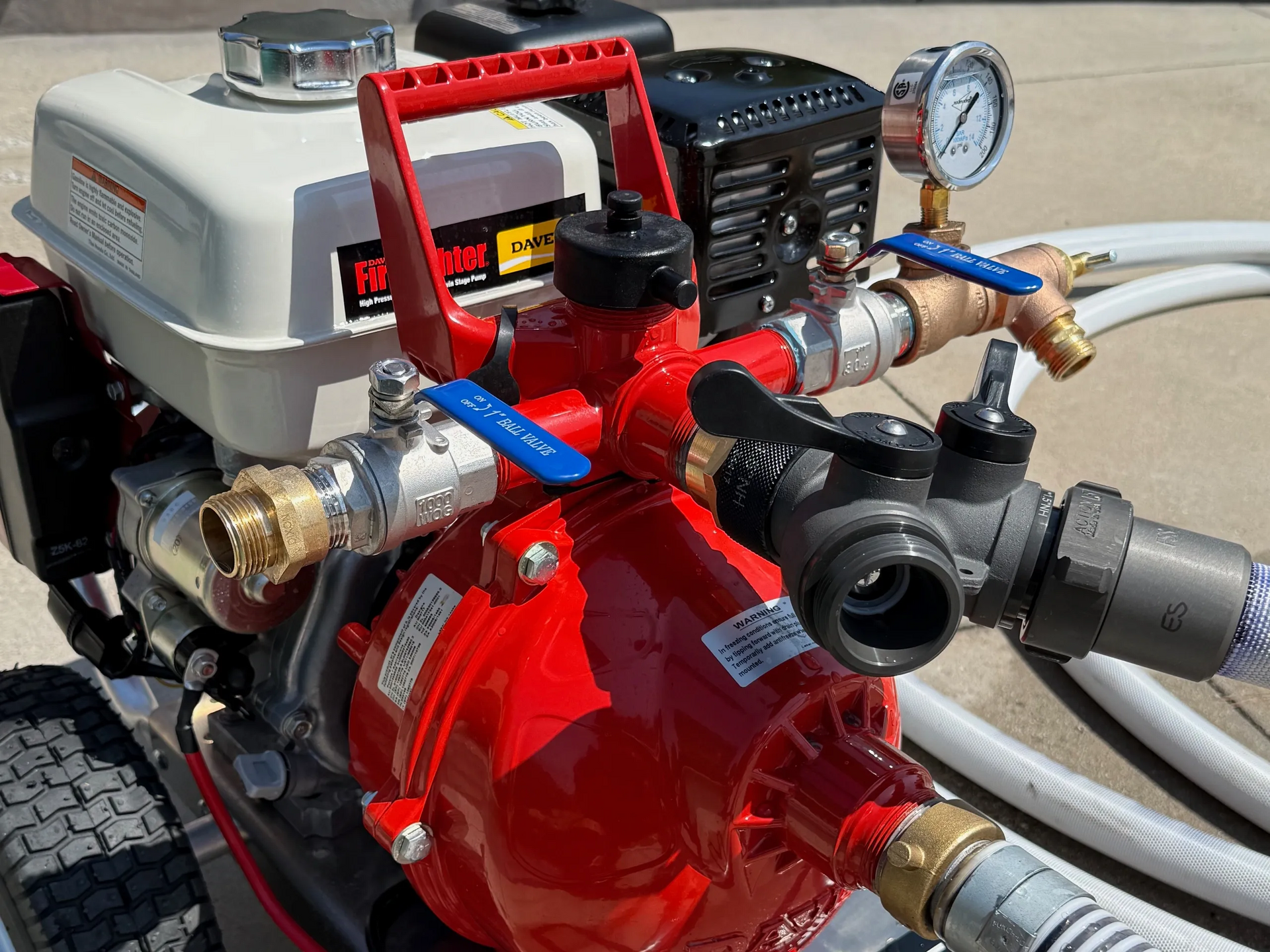 Red portable water pump with a handle, valves, and pressure gauge, likely for agricultural or construction use.
