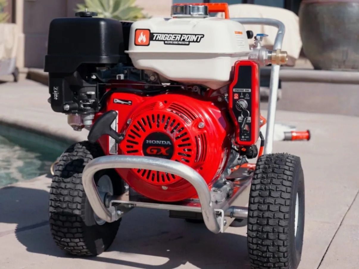 Red and white pressure washer with a Honda engine on a paved surface.