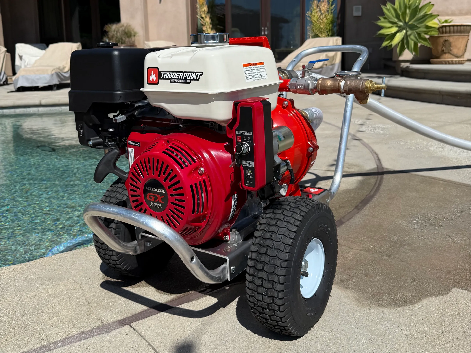 Red and black pressure washer with a Honda engine, near a pool.