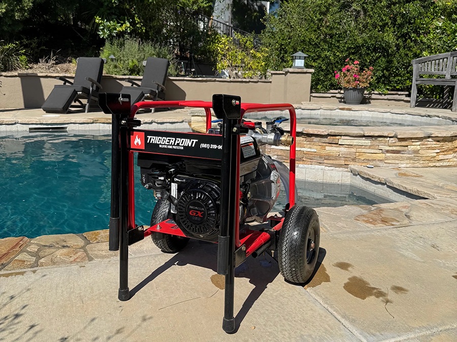 Red pressure washer on wheels next to a swimming pool.