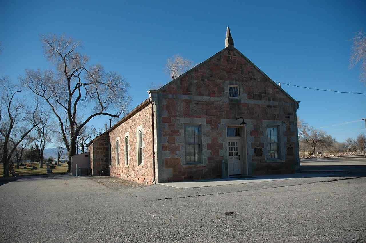An old brick building is sitting in the middle of a gravel road.