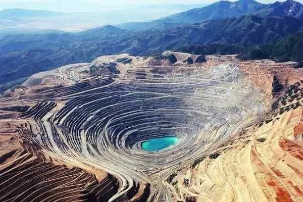 An aerial view of a large open pit mine with mountains in the background.