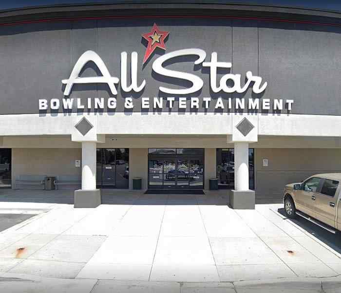 An all star bowling and entertainment building with a truck parked in front of it