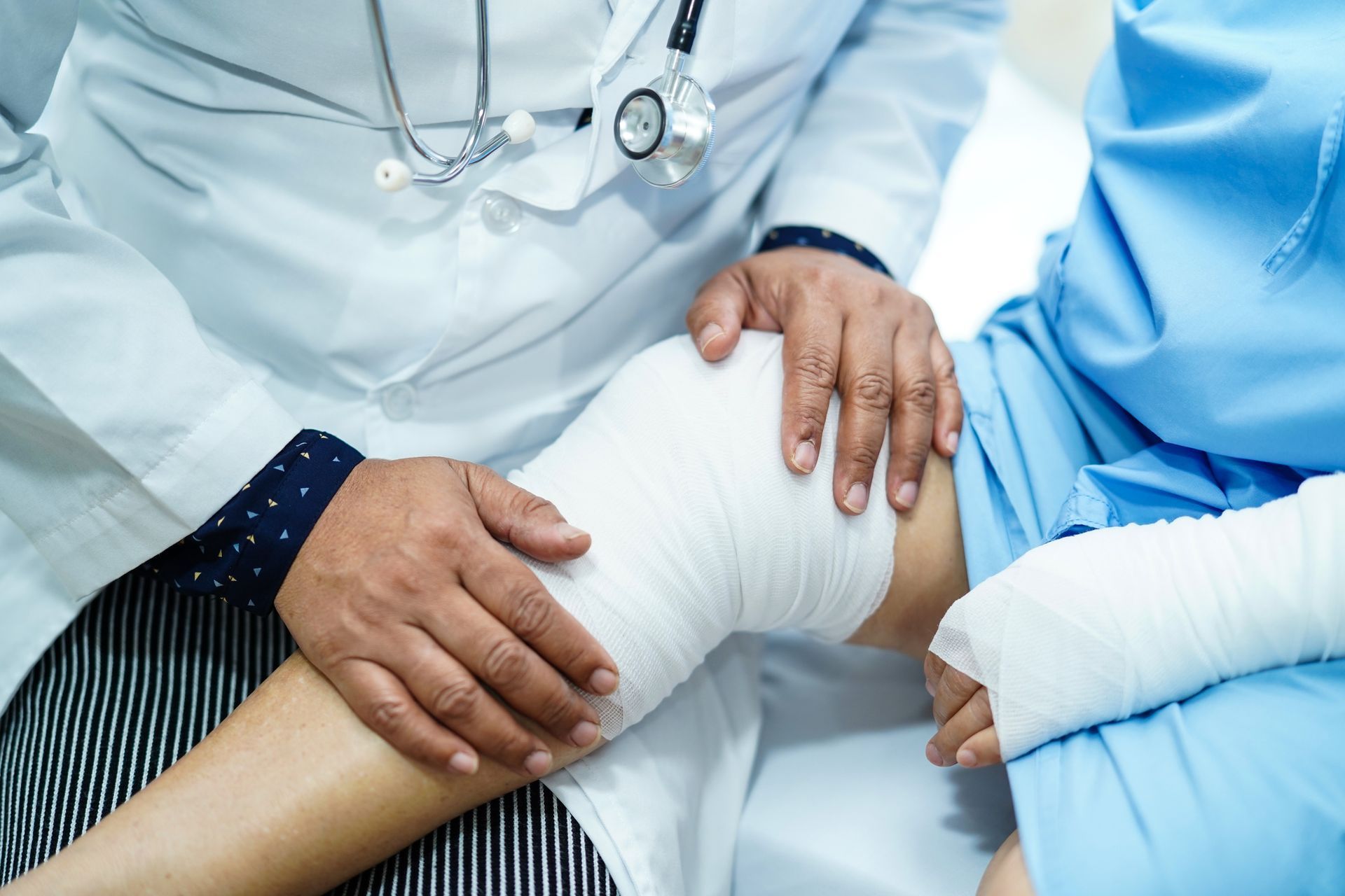 A doctor is bandaging a patient 's knee in a hospital bed - New City, NY - A & T Certified