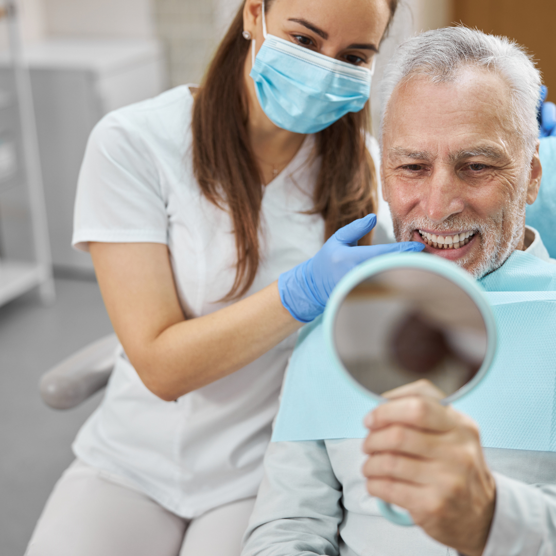 Dental Patient Looking at his new teeth in mirror happy with dentist