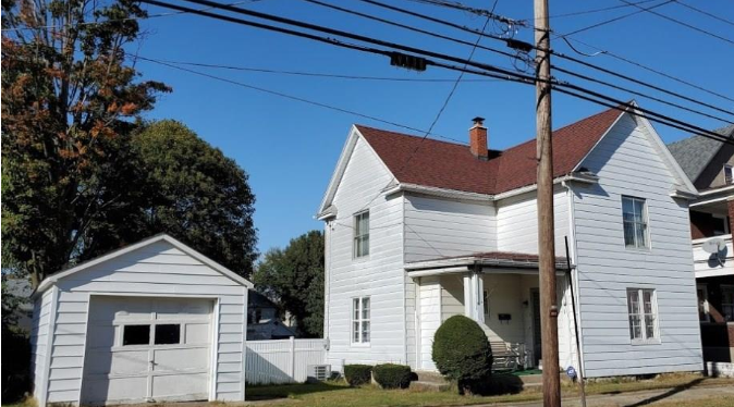 White two-story house with a garage and brown roof under a blue sky.