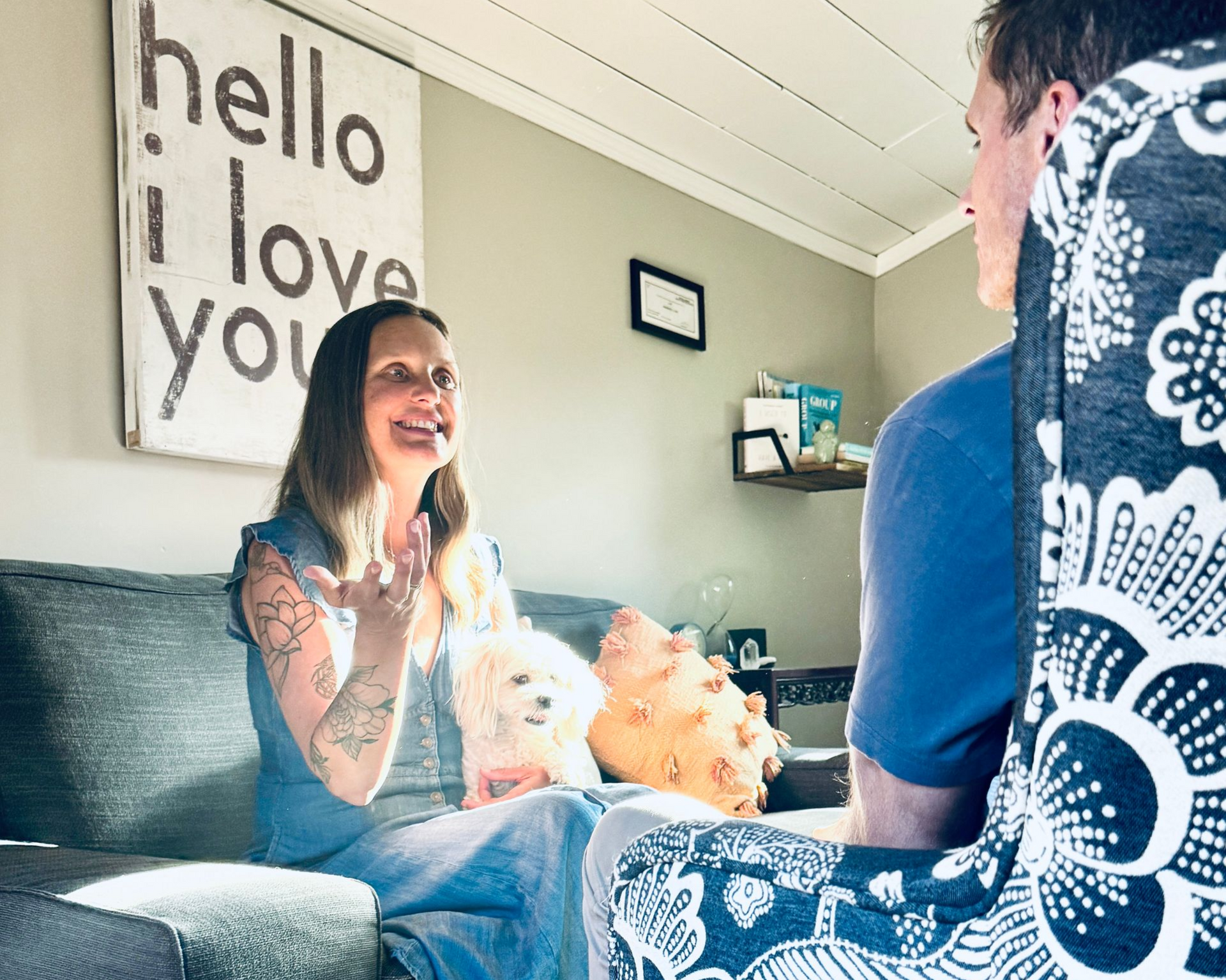 A woman is sitting on a couch talking to a woman.