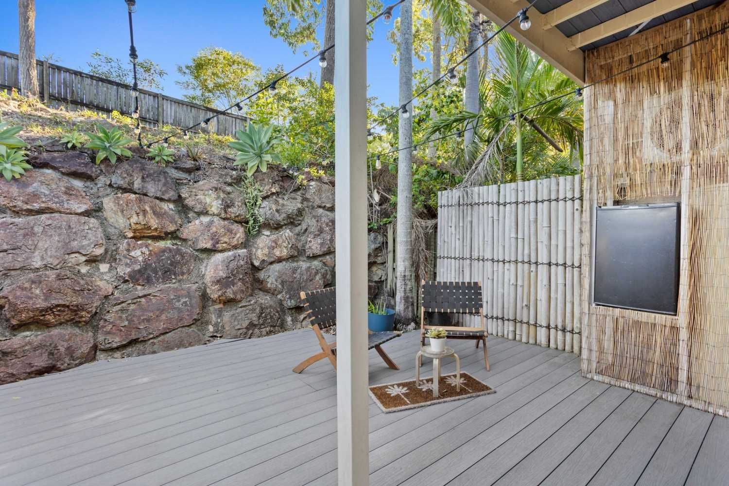 A Patio With a Wooden Deck and a Stone Wall — JPR Concepts in Burleigh Heads, QLD