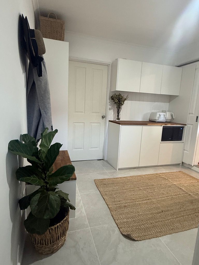 Bright Entryway with White Cabinets and Wall Hooks Next to A Small Kitchen Area — JPR Concepts in Burleigh Heads, QLD