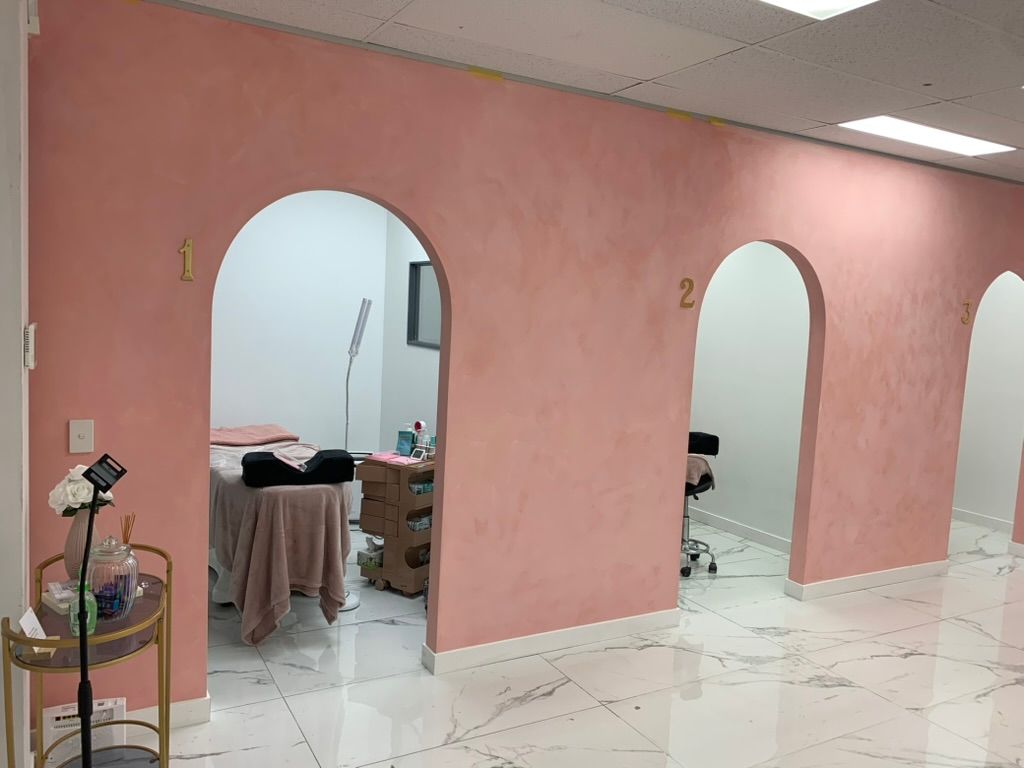 Pink Salon Interior with Arched Doorways, Treatment Chairs, and Glossy White Tile Floor — JPR Concepts in Burleigh Heads, QLD