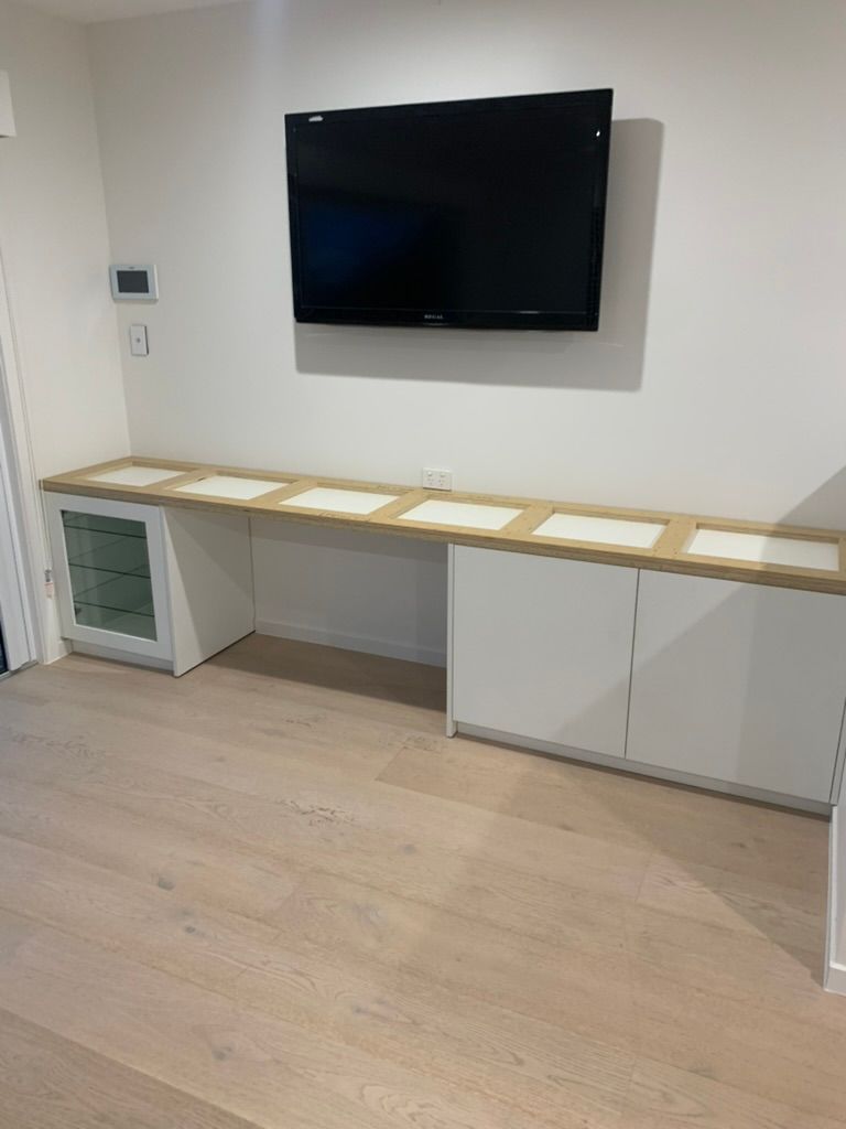 Modern Room with Wall Mounted TV Above a Long White Counter and Cabinet — JPR Concepts in Burleigh Heads, QLD