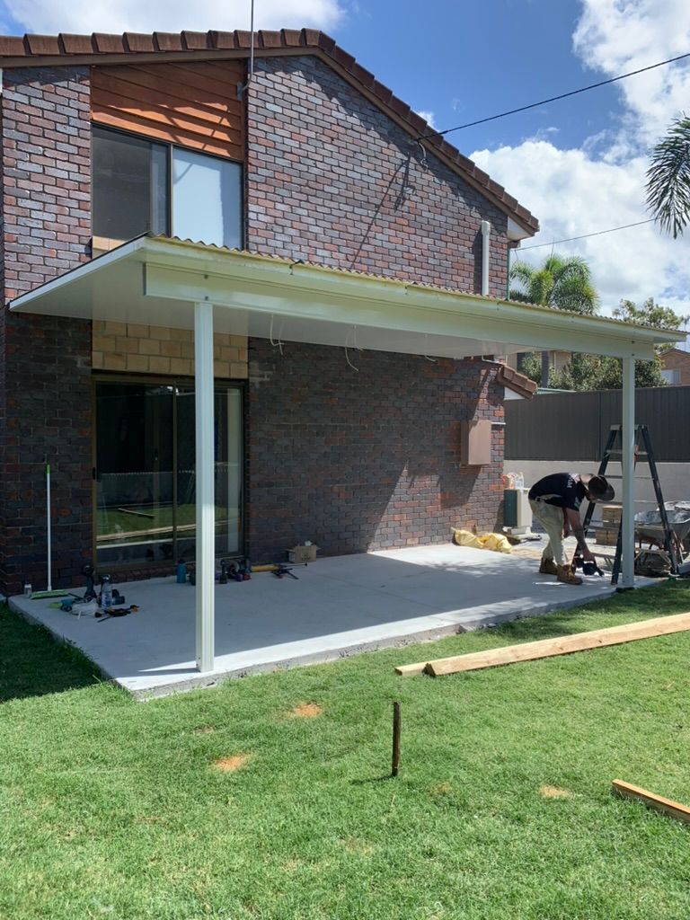 Brick House Patio with White Roof, Sliding Glass Door, and Lawn Under a Blue Sky — JPR Concepts in Burleigh Heads, QLD