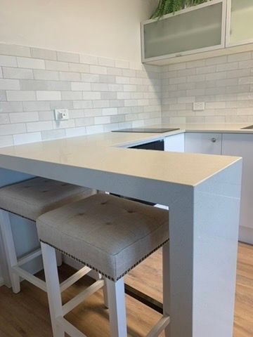 Modern Kitchen with White Tile Backsplash and Two Cushioned Stools at A Breakfast Bar — JPR Concepts in Burleigh Heads, QLD