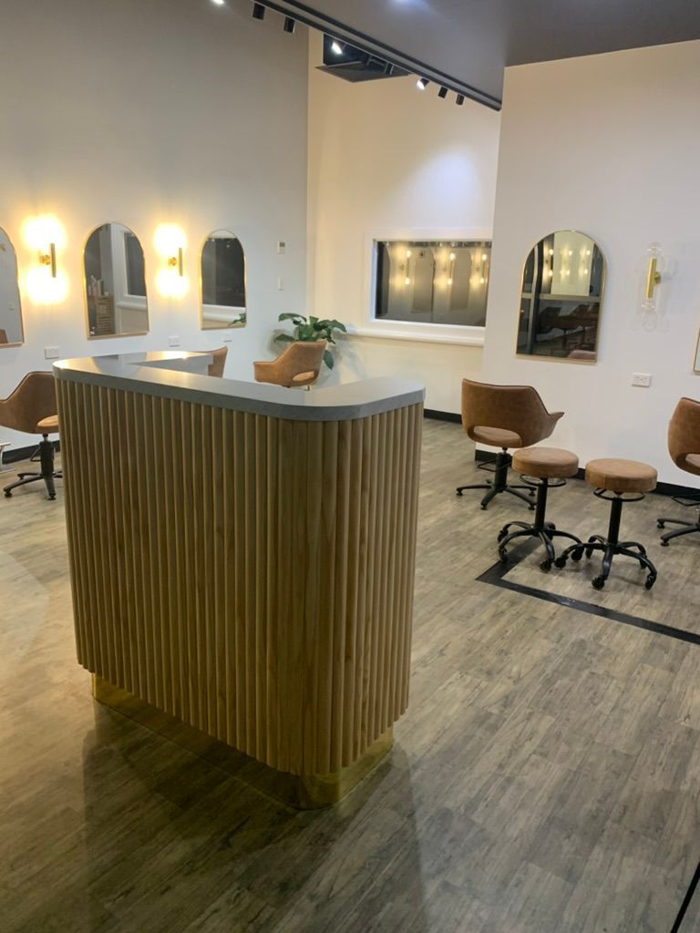 Modern Salon Interior with Wood Counter, Styling Chairs, and Warm Wall Sconces — JPR Concepts in Burleigh Heads, QLD