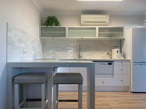 Modern White Kitchen with Island Table, Stools, and Wall Cabinets — JPR Concepts in Burleigh Heads, QLD