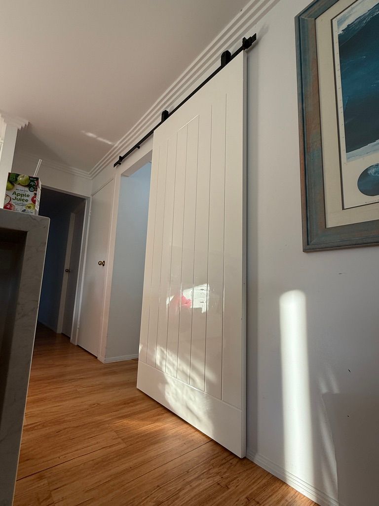 White Barn Door Closet in A Hallway with Wood Floors and A Framed Picture on The Wall — JPR Concepts in Burleigh Heads, QLD