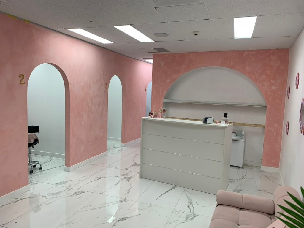 Pink Reception Area with Arched Doorways, Marble Floor, and A White Desk — JPR Concepts in Burleigh Heads, QLD