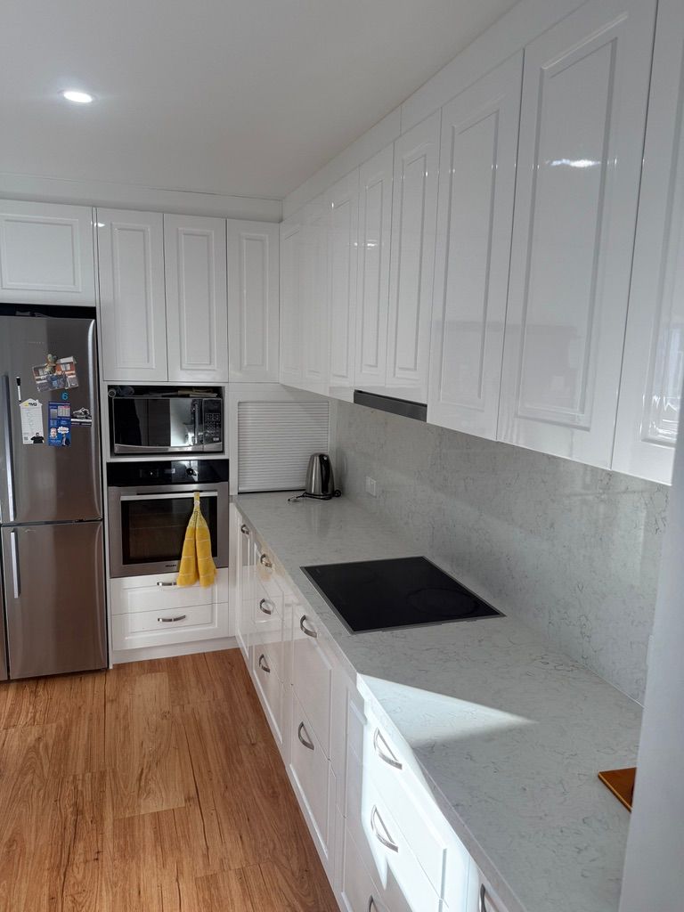 Bright White Kitchen with Stainless Fridge, Built In Microwave, and Wood Floor — JPR Concepts in Burleigh Heads, QLD