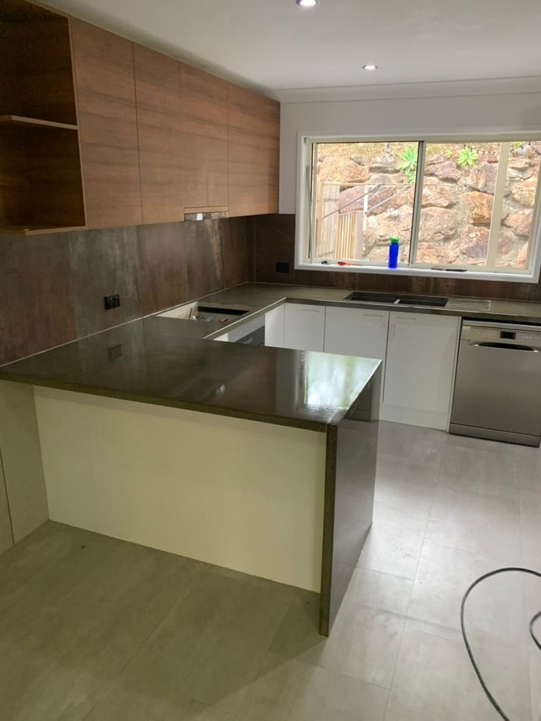 Modern Kitchen with Cabinets, Dark Countertop Island, Wood Backsplash, and Large Window — JPR Concepts in Burleigh Heads, QLD