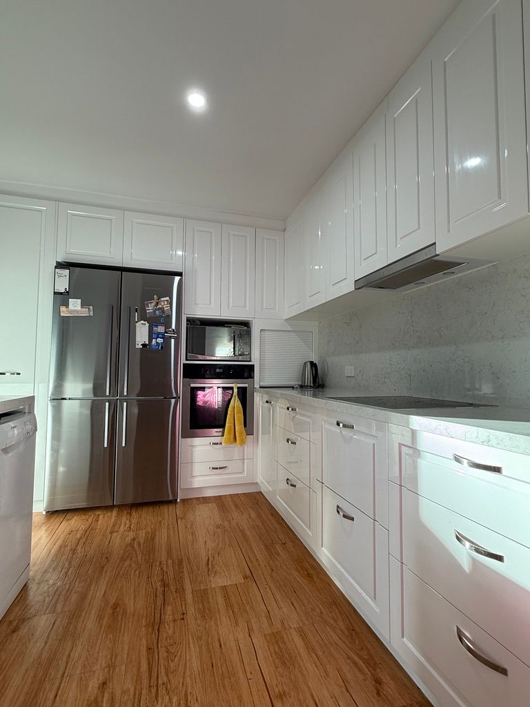 Modern White Kitchen with Stainless Steel Refrigerator and Wood Flooring — JPR Concepts in Burleigh Heads, QLD
