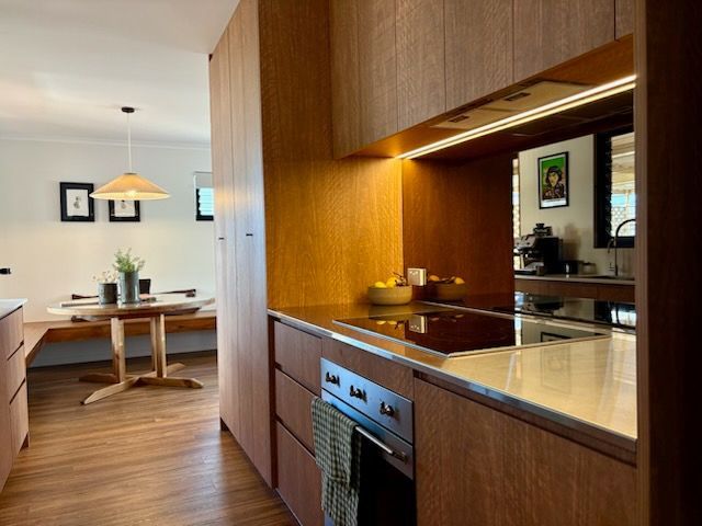 Modern Kitchen with Wood Cabinets and Dining Area in The Background — JPR Concepts in Burleigh Heads, QLD