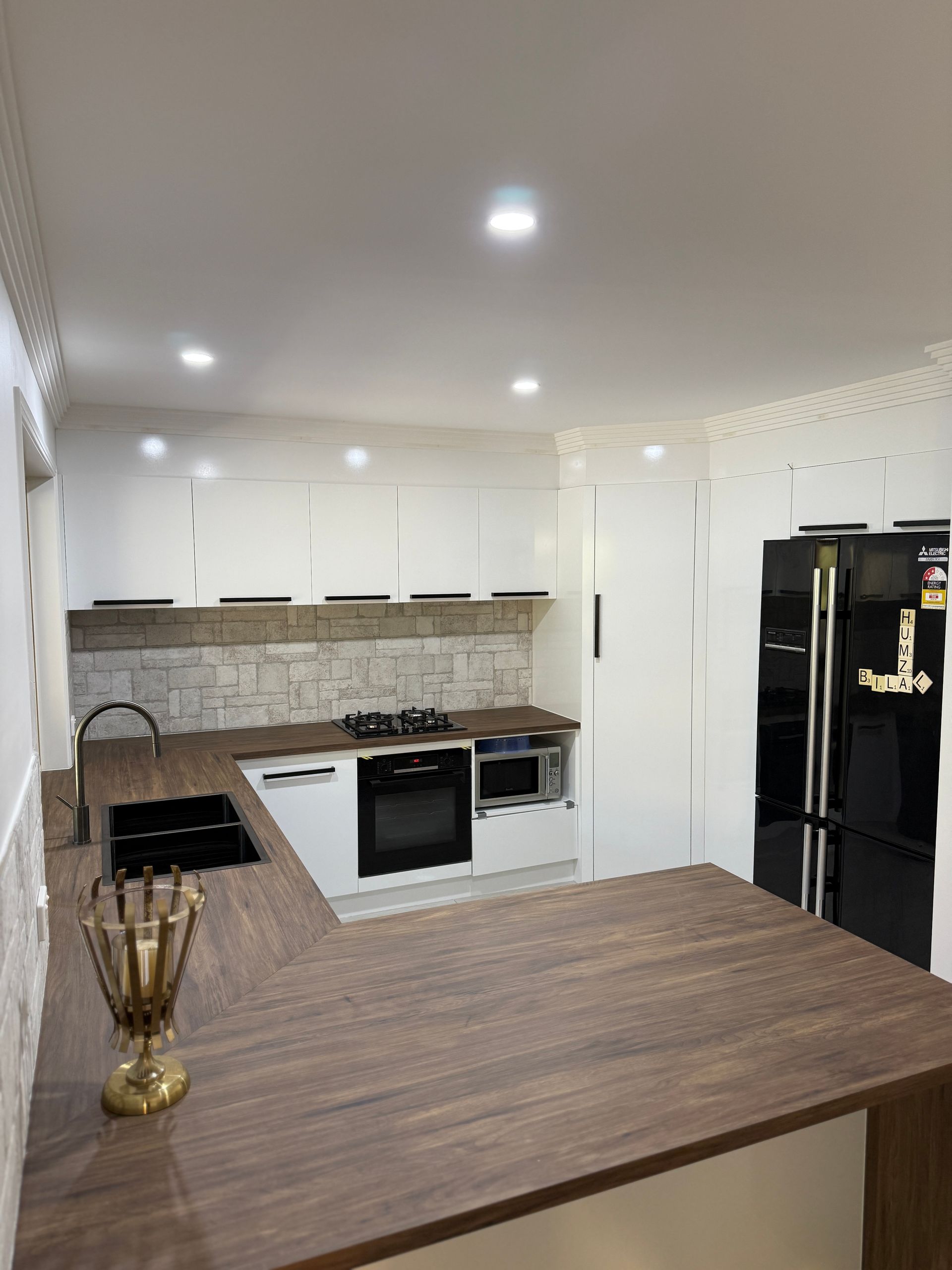 Modern White Kitchen with Stone Backsplash and A Wooden Island in The Foreground — JPR Concepts in Burleigh Heads, QLD