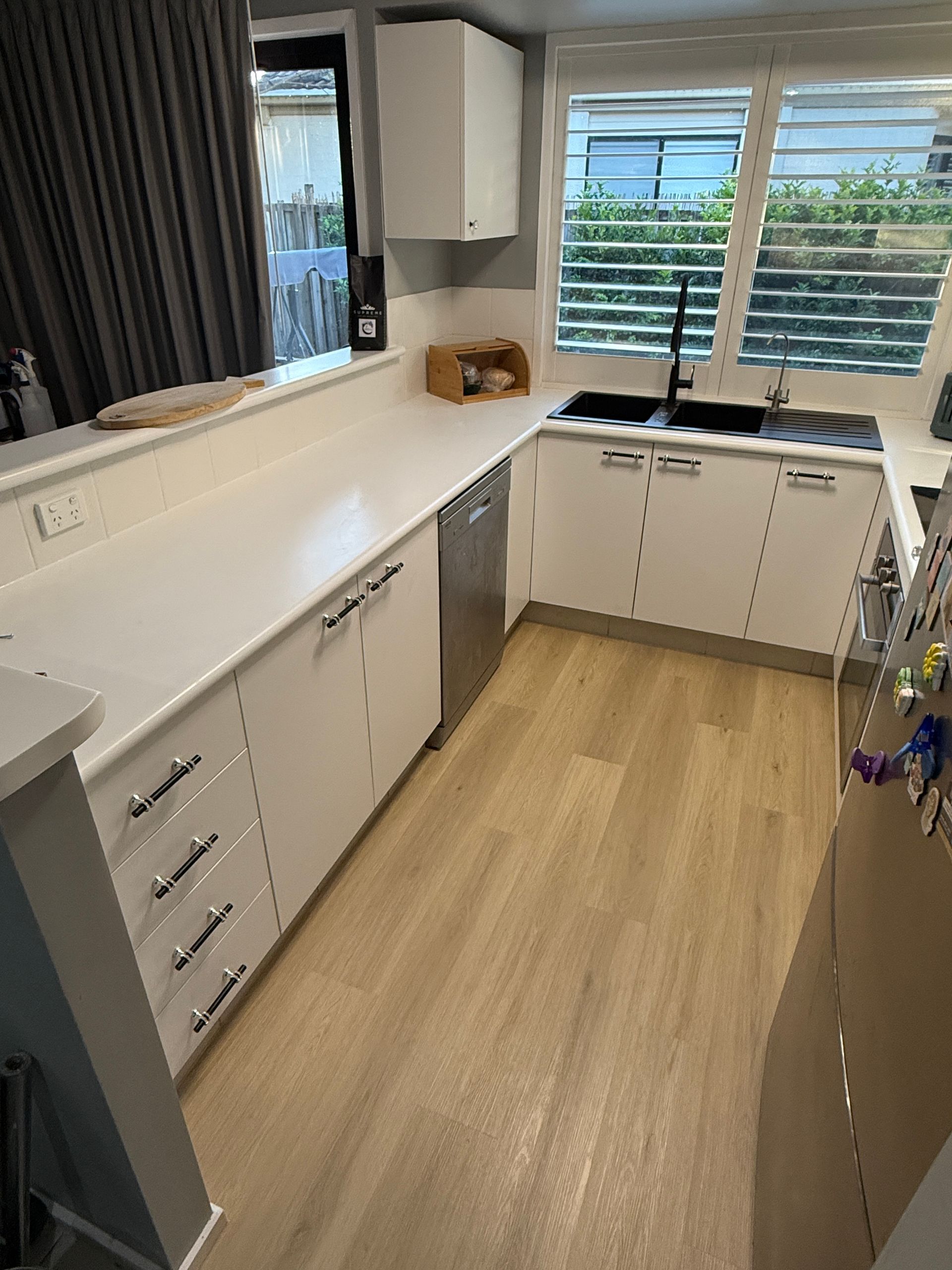 Narrow Modern Kitchen with White Cabinets and Light Wood Floor — JPR Concepts in Burleigh Heads, QLD