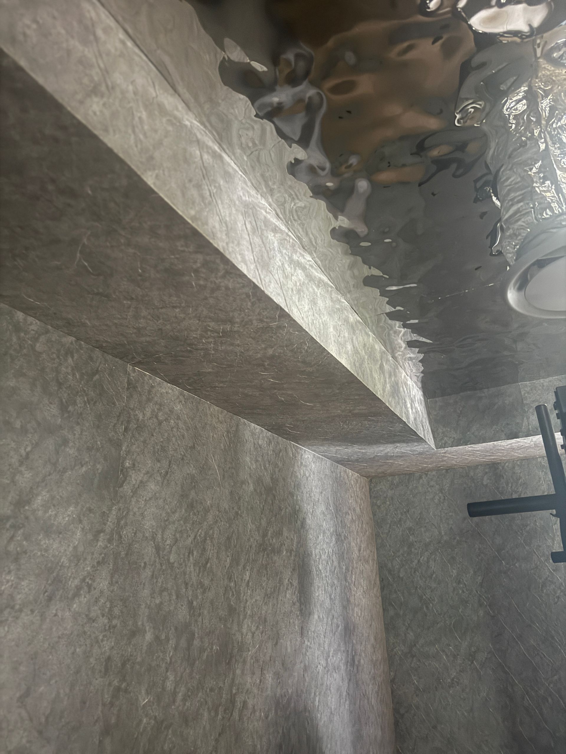 Wet Concrete Basement Corner with A Metal Duct and A Dark Pipe Against Gray Walls — JPR Concepts in Burleigh Heads, QLD