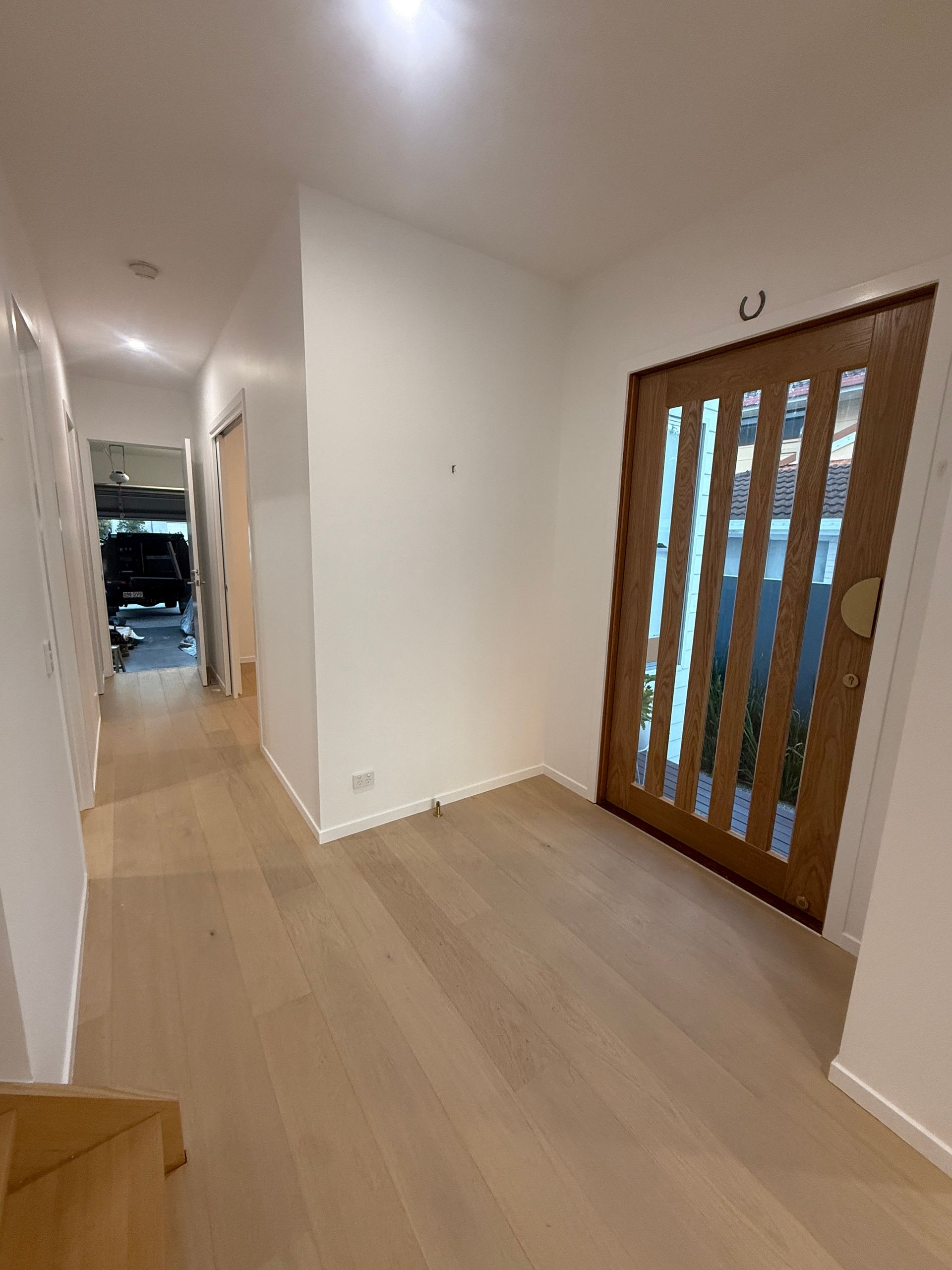 Empty Hallway with Light Wood Floors and A Wooden Glass Paneled Front Door — JPR Concepts in Burleigh Heads, QLD